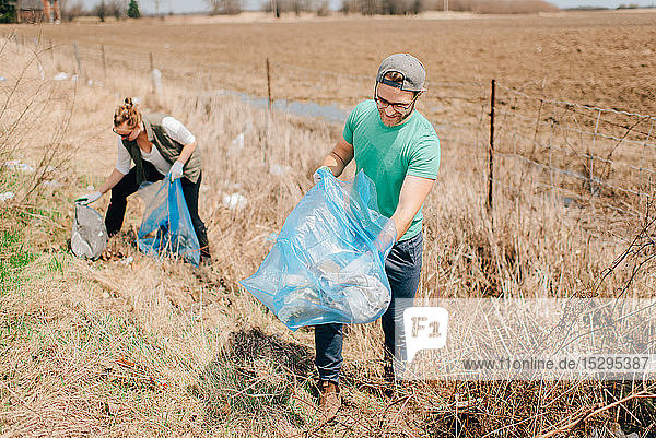 Couple picking up rubbish by field  Georgetown  Canada