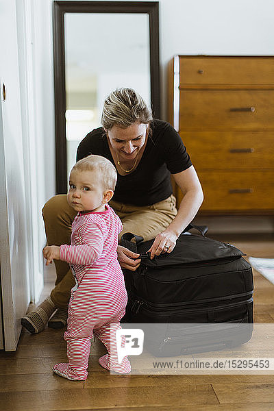 Mutter im Gepäck mit Baby im Schlafzimmer