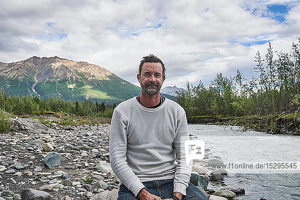 Man relaxing by stream  scenic view in background  Chitina  Alaska  United States
