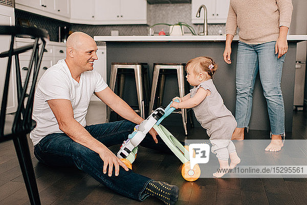 Mother father playing with baby daughter in kitchen