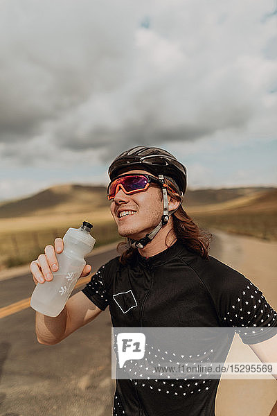 Junger männlicher Radfahrer mit einer Wasserflasche in der Hand auf einer Landstraße  Exeter  Kalifornien  USA