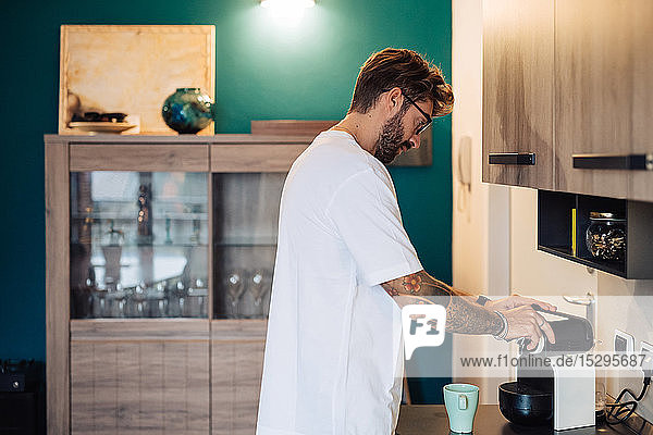 Mittelgroßer erwachsener Mann bereitet Kaffeemaschine auf der Küchentheke vor