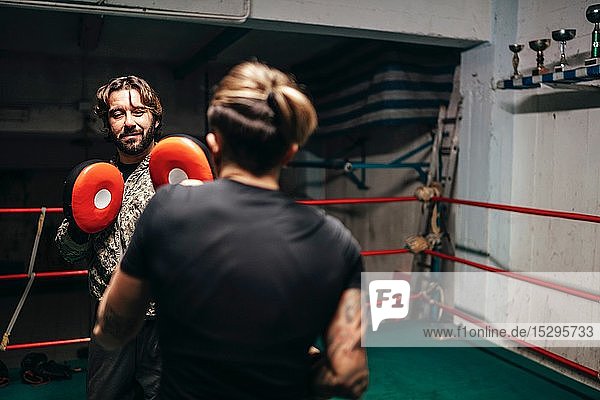 Boxer sparring with trainer in boxing ring