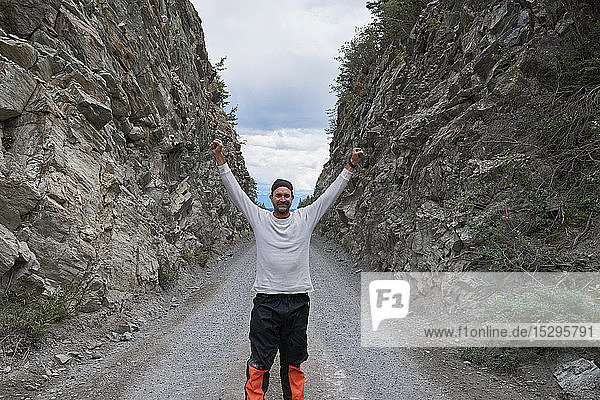 Mann hebt die Hände zwischen felsigen Hügeln  Chitina  Alaska  Vereinigte Staaten