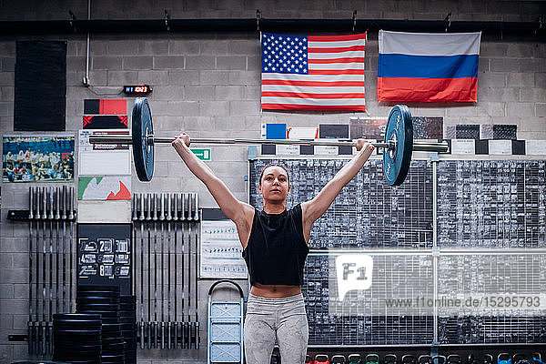 Young woman lifting barbell in gym