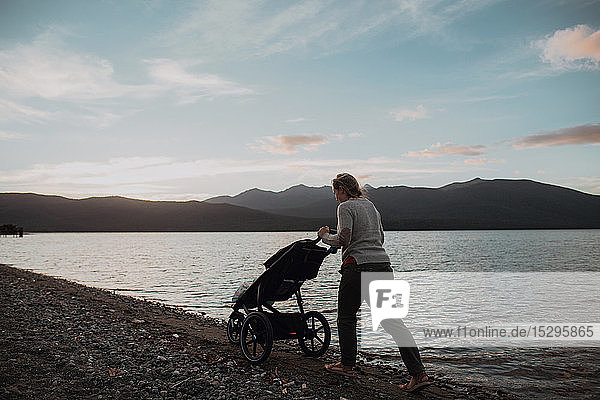 Mother with baby in pram walking on beach  Te Anau  Southland  New Zealand