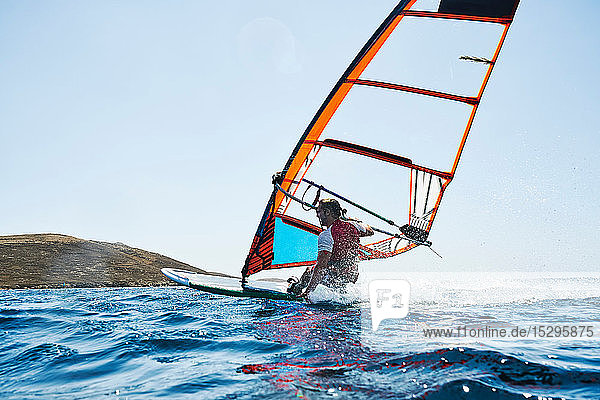 Zurückgelehnter junger Mann beim Windsurfen auf Meereswellen  Rückansicht auf Oberflächenniveau  Limnos  Khios  Griechenland