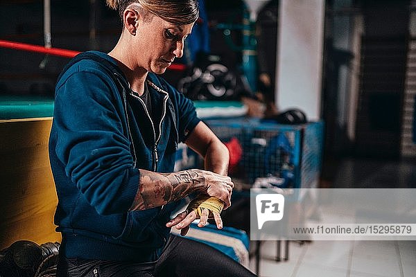 Boxer putting on handwrap in gym