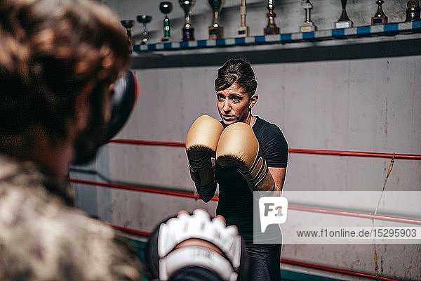 Boxer sparring with trainer in boxing ring