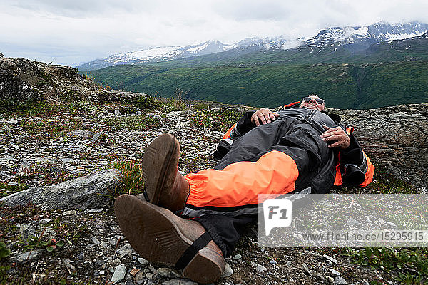 Älterer männlicher Wanderer macht eine Pause auf dem Gipfel eines Berges liegend  Valdez  Alaska  USA