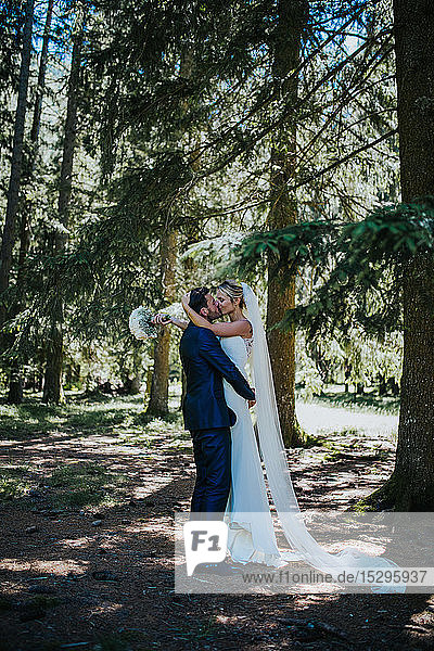 Romantischer Bräutigam hebt die Braut zum Kuss im Wald
