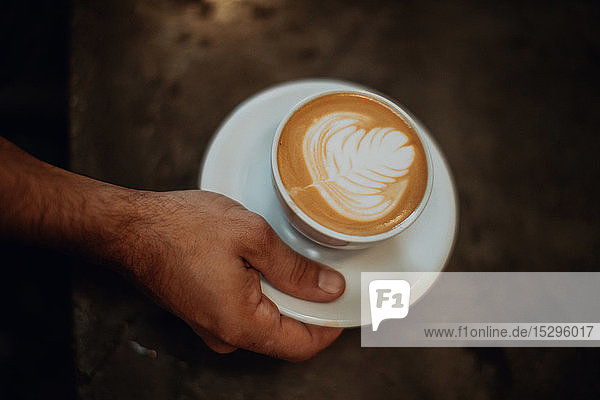 Barista stellt Becher mit Milchkaffee auf die Theke des Cafés  über Kopf in Nahaufnahme der Hand