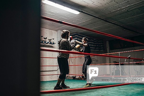Boxer sparring with trainer in boxing ring