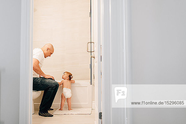 Vater mit Baby-Tochter bereitet Bad vor