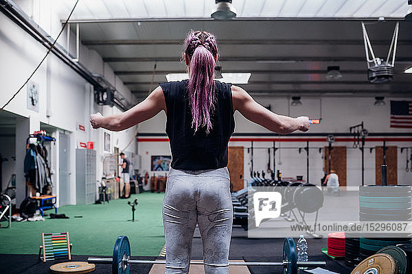 Young woman preparing to lift barbell in gym