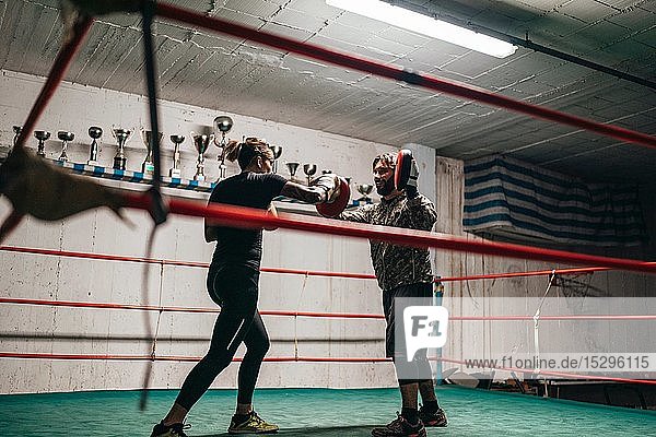 Boxer sparring with trainer in boxing ring