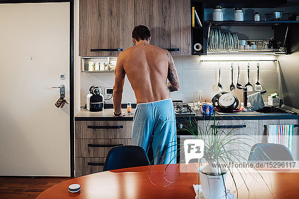 Mittelgroßer erwachsener Mann  der das Frühstück am Küchenherd zubereitet  Rückansicht