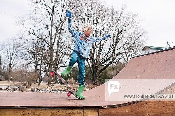 Junge auf ländlicher Skateboard-Rampe beim Üben eines Skateboard-Tricks
