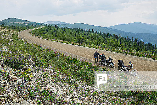 Älterer männlicher Motorradfahrer am ländlichen Bergstraßenrand mit Motorrad  Hochwinkelporträt  Dawson Creek  Kanada