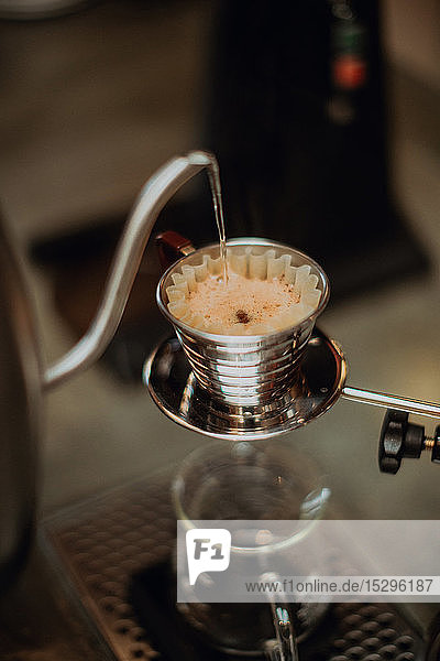 Gekochtes Wasser aus dem Wasserkocher  das in den Kaffeefilter auf der Kaffeetheke läuft  Nahaufnahme flacher Fokus
