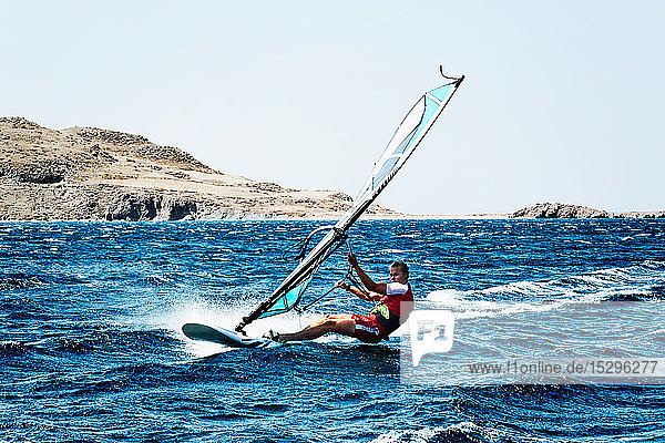 Junger Mann beim Windsurfen auf Meereswellen Limnos Khios Griechenland