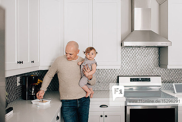 Father carrying baby daughter in kitchen  portrait