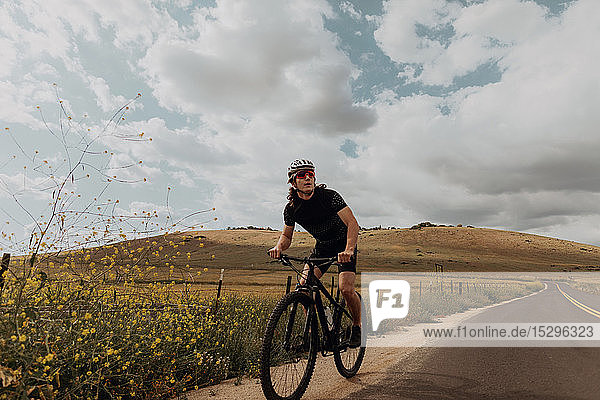 Junger männlicher Radfahrer  der beim Radfahren auf einer Landstraße wegschaut  Exeter  Kalifornien  USA