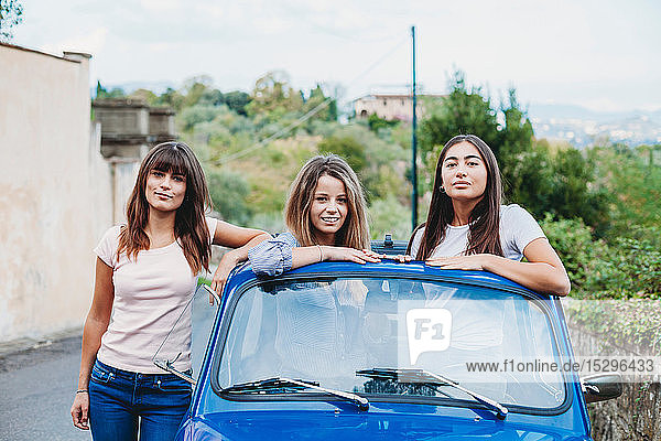 Frau steht neben Freunden und posiert im Autoschiebedach  Florenz  Toskana  Italien