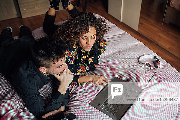 Ehepaar mit Laptop auf dem Bett