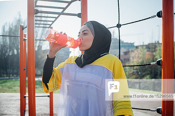 Calisthenics class at outdoor gym  young woman drinking from water bottle