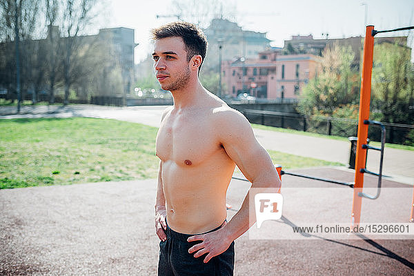 Gymnastik im Freien  junger Mann mit nacktem Oberkörper macht eine Pause