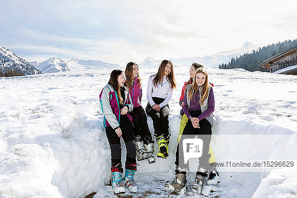 Fünf jugendliche Skifahrerinnen sitzen lachend in verschneiter Landschaft  Tirol  Steiermark  Österreich