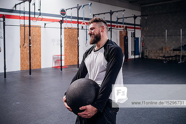 Young man training  lifting atlas ball in gym