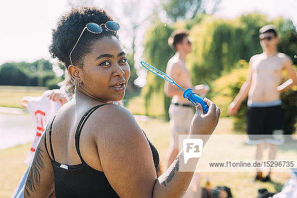 Young woman blowing bubbles in park