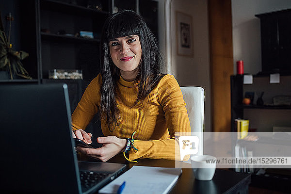 Woman using smartphone in home office