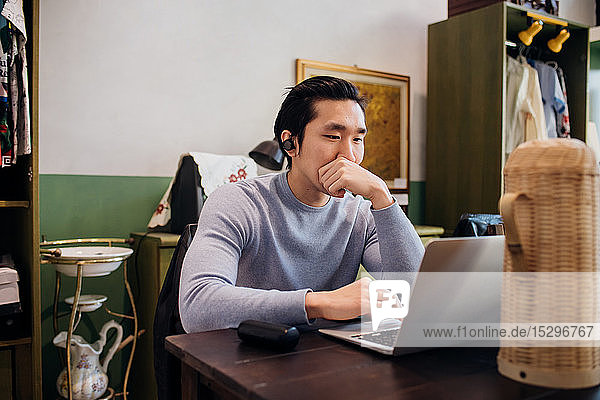 Junger Geschäftsmann arbeitet ferngesteuert am Laptop am Cafétisch
