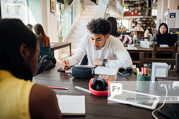 Young businessman and woman remote working at cafe table