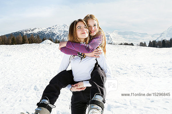 Teenager-Skifahrerin wird von bester Freundin in verschneiter Landschaft huckepack genommen  Porträt  Tirol  Steiermark  Österreich