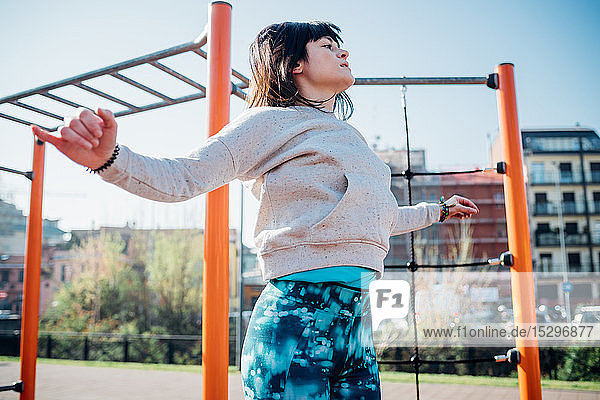 Calisthenics class at outdoor gym  young woman jumping with arms outstretched