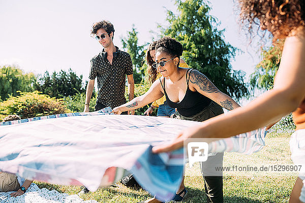 Freunde legen Picknickdecke im Park aus