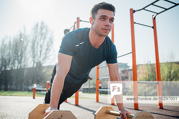 Gymnastik im Freien  junger Mann macht Liegestütze an Fitnessgeräten