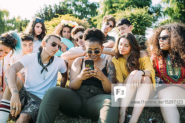 Gruppe von Freunden benutzt Smartphone im Park