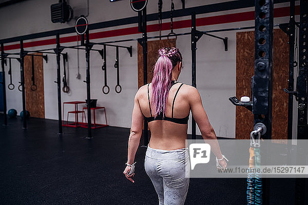 Young woman with purple ponytail training in gym  rear view