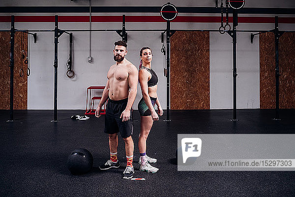 Junge Frau und Mann trainieren zusammen  Rücken an Rücken Portrait im Fitnessstudio