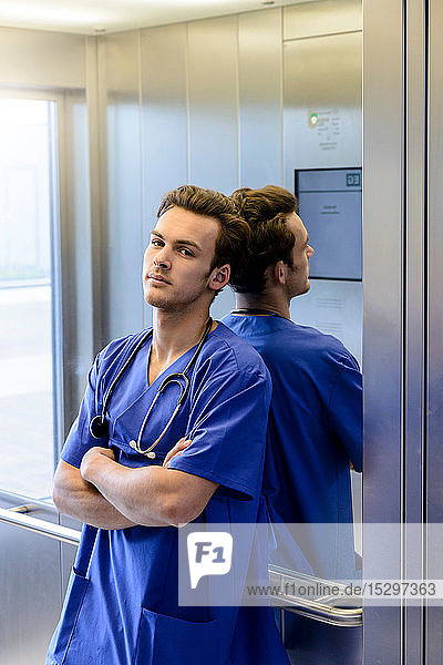 Junger männlicher Assistenzarzt im Krankenhausaufzug  Porträt