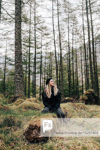 Frau sitzt auf einem Baumstamm  Trossachs-Nationalpark  Kanada