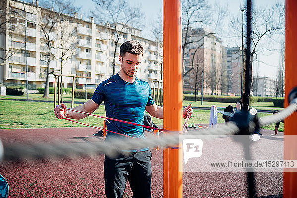 Calisthenics at outdoor gym  young man stretching arms on exercise equipment