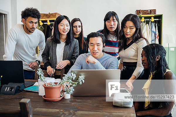 Gruppe junger Geschäftsleute betrachtet Laptop in Bürobesprechung