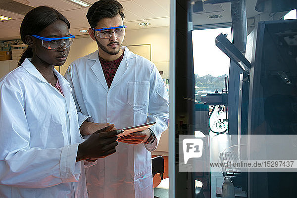Junge Wissenschaftlerinnen und Wissenschaftler sehen sich wissenschaftliche Geräte im Labor an