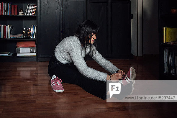 Woman putting on walking shoes on floor